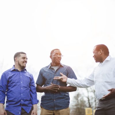 A group of diverse male friends talking to each other and smiling